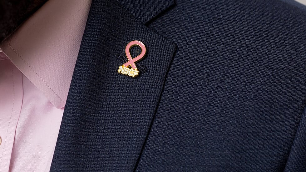 Pink ribbon pin placed on a suit near the neck